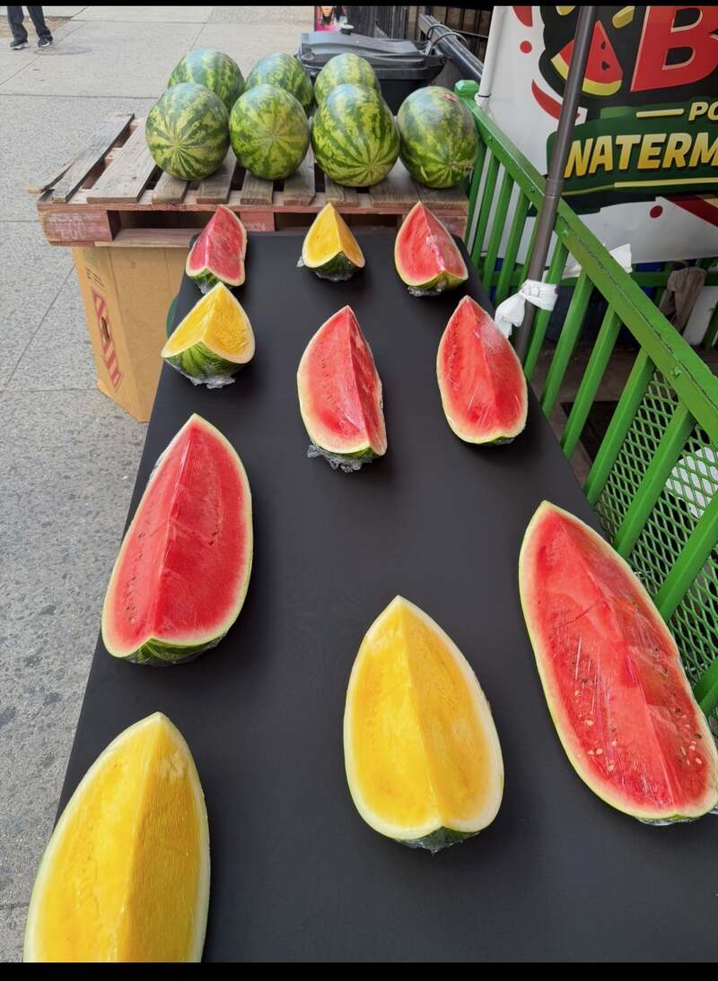 Red and yellow watermelon halves laid out on the sidewalk table