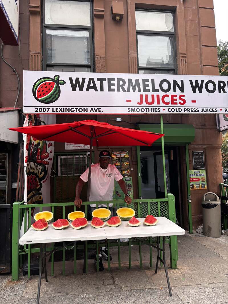 The owner behind the sidewalk table of cut watermelon